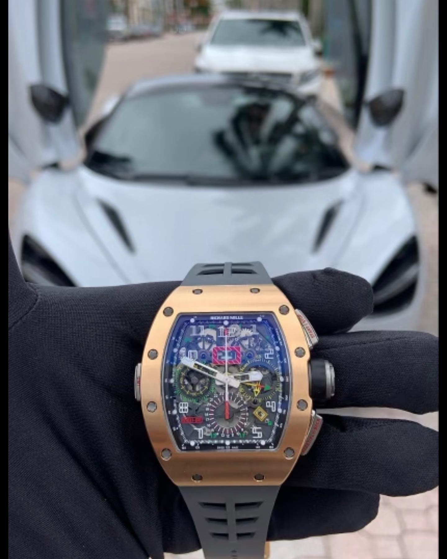 Luxury watch held in front of an exotic sports car